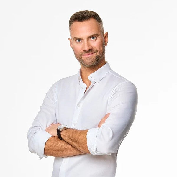 Our Jakub wearing a white shirt with arms crossed on a light gray background